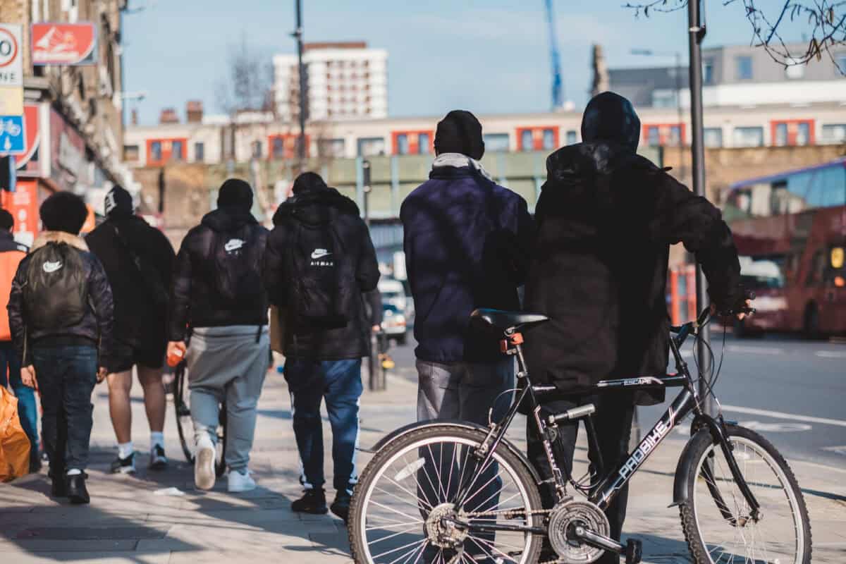 Groepje jongens in donkere kleding en hoofd- en gezichtsbedekking loopt door de stad.