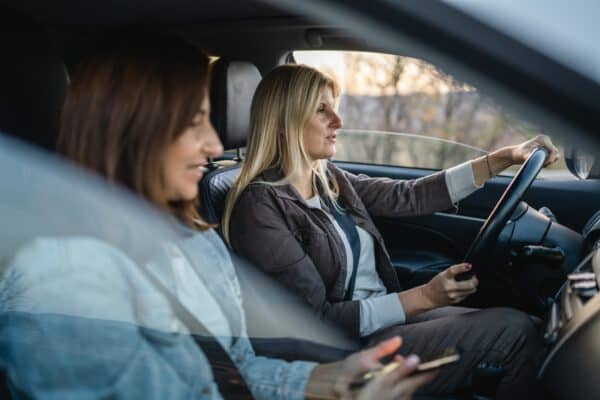 Jeugdbeschermer en moeder zitten te praten in een auto.