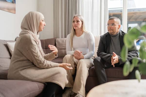 Jeugdbeschermer op de bank in gesprek met ouders.